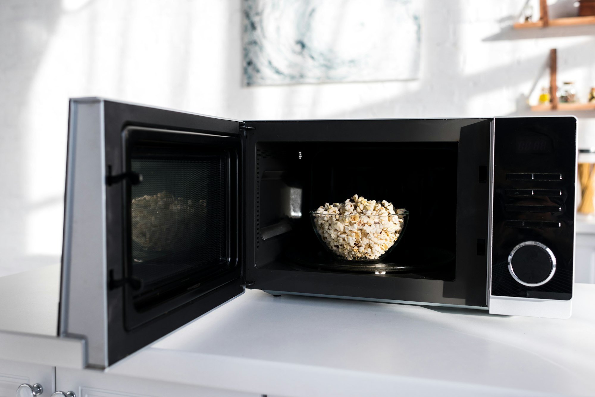 bowl with popcorn in opened microwave in kitchen